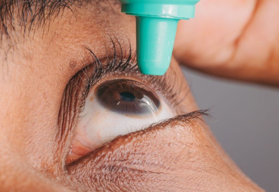 an eye with a eye drop bottle near it